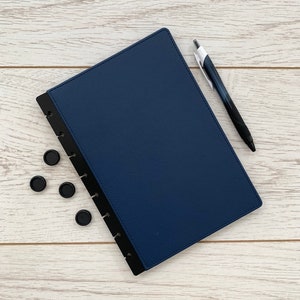 A dark blue faux leather A5 discbound planner cover with black disc-bound edging and slightly rounded corners