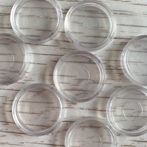 May include: Eight clear plastic round furniture pads with a smooth surface. The pads are designed to protect floors from scratches.