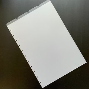 May include: White paper with tabs and a row of holes down the left side. The paper is on a black surface.