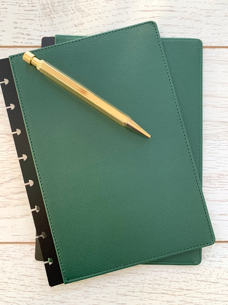 A Forest green faux leather Discbound planner cover, slightly larger than A5 sized paper, with black polypropylene mushroom hole punched edges