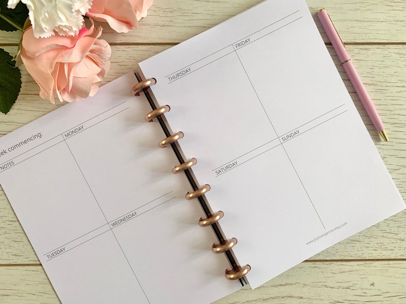 May include: A white weekly planner with a rose gold coil binding. The planner has spaces for each day of the week, Monday through Sunday, with a section for notes and a space for the week commencing.