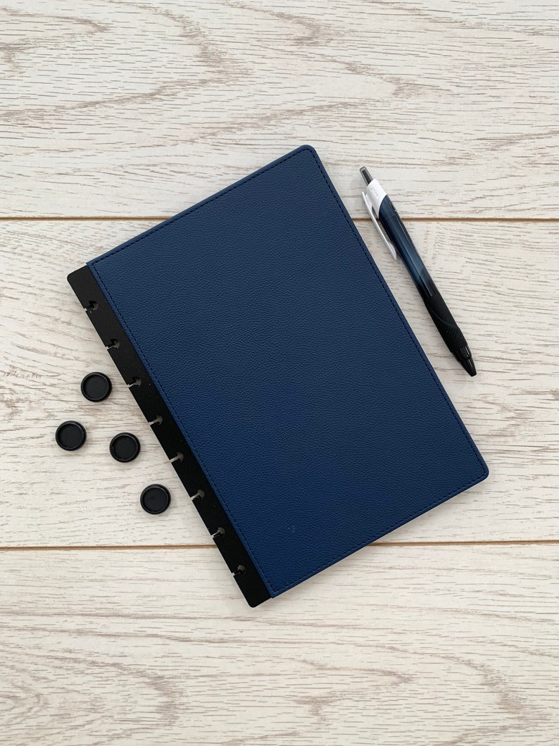 A dark blue faux leather A5 discbound planner cover with black disc-bound edging and slightly rounded corners
