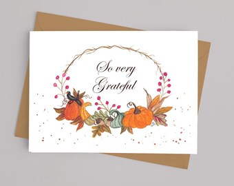 May include: A watercolor greeting card with the words "So very Grateful" inside a wreath of fall foliage. The wreath includes pumpkins, leaves, berries, and corn. The card is on a white background, inside a brown envelope.