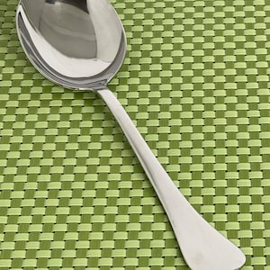 May include: A polished silver-coloured metal spoon with a wide, rounded bowl and a smooth, tapered handle. The surface of the spoon is reflective, showing a clear metallic sheen. The design is simple and functional, featuring a curved neck.