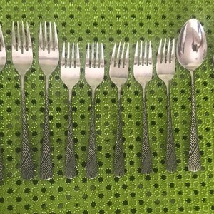 May include: A set of silverware with a wavy pattern on the handles. The set includes knives, forks, and spoons.