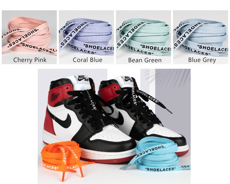 May include: A pair of black and red high-top sneakers with white laces. The sneakers are sitting on a white surface with four different colored shoelaces in the background. The shoelaces are labeled "SHOELACES" in black text. The colors of the shoelaces are cherry pink, coral blue, bean green, and blue grey.