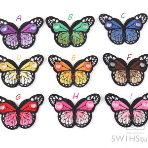 May include: Nine embroidered butterfly shoe charms in various colors, including purple, green, blue, yellow, orange, brown, red, pink, and white. Each charm has two eyelets for attaching to shoes.