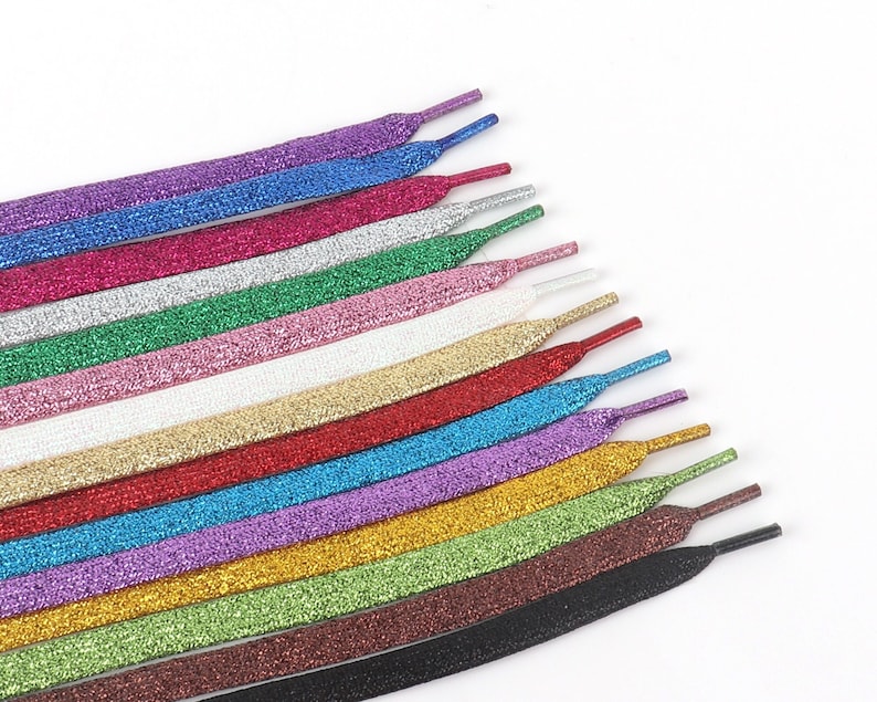 May include: A set of 18 colorful shoelaces with a sparkly glitter finish. The laces are arranged in a fan shape, with the black lace at the bottom and the purple lace at the top.