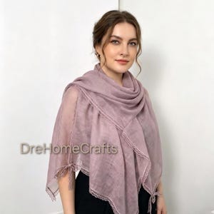 May include: A dusty rose-colored scarf featuring a lightweight, semi-sheer fabric with delicate lace trim along the edges and small decorative ties at the corners. The text DreHomeCrafts is visible on the left side of the scarf fabric.