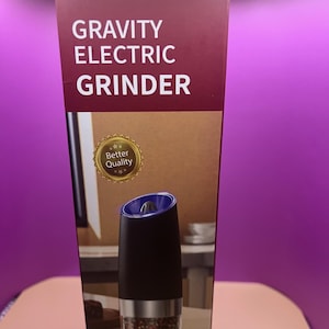 May include: A black and silver gravity electric grinder with a clear container filled with peppercorns. The box reads "GRAVITY ELECTRIC GRINDER" in white text. A gold seal reads "Better Quality". Battery operated.