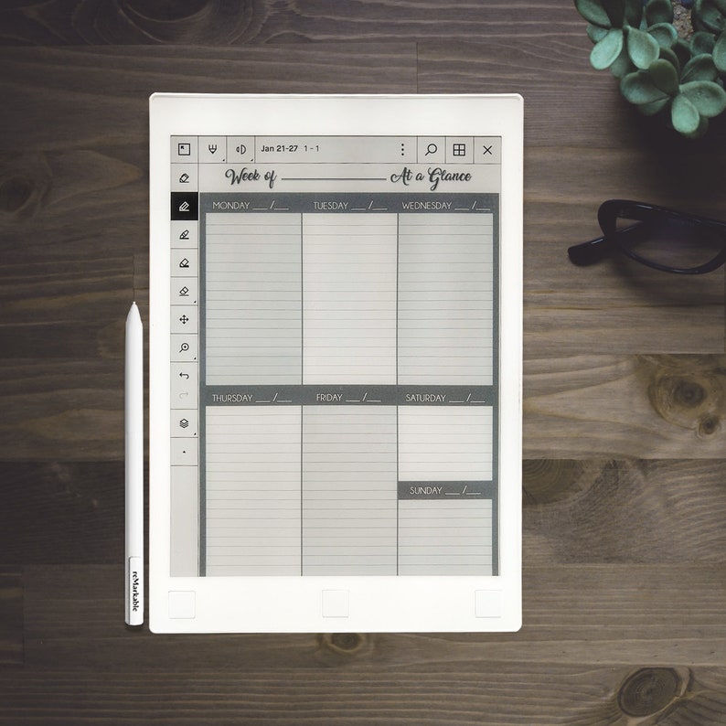 Pu&ograve; includere: Un e-reader bianco con uno stilo nero e grigio. Lo schermo mostra un planner settimanale con il testo "Week of" e "At a Glance". Le date sono "Jan 21-27 1-1".