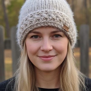 Peut inclure: Un bonnet en tricot gris clair avec une bande texturée et une petite étiquette en cuir marron. Le chapeau est fait de fil doux et duveteux. Un accessoire d'hiver.