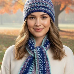 May include: A crochet beanie and a matching scarf featuring a multi-coloured pattern of dark blue, light blue, and muted purple yarn. The beanie is a fitted style, and the scarf is a long, rectangular piece with a textured, repeating stitch design.