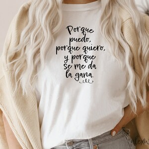May include: White t-shirt with black text that reads "Porque puedo, porque quiero, y porque se me da la gana."