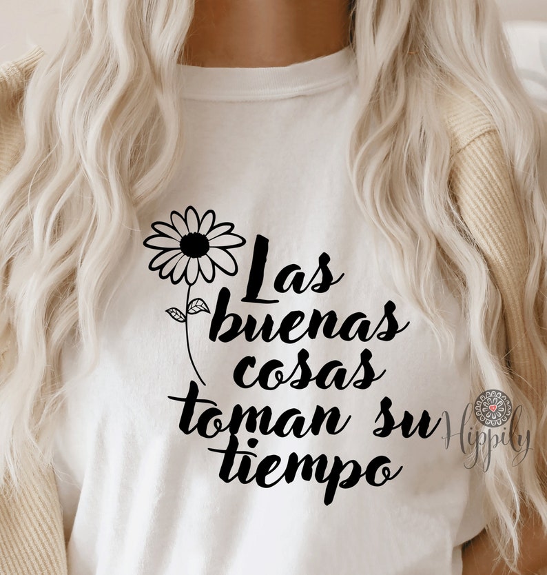 Puede incluir: Camiseta blanca con una margarita negra y el texto "Las buenas cosas toman su tiempo" impreso en la parte delantera.