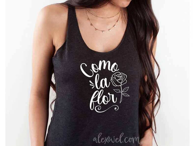 May include: A black tank top with a white graphic that says "Como la flor" with a stylized rose illustration. The text is in a cursive font.
