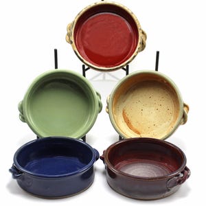 May include: Set of four ceramic ramekins with handles. The ramekins are in various colors, including red, green, blue, and brown.