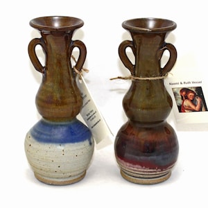 May include: Two brown and blue ceramic vases with handles. The vases are decorated with a brown glaze and a blue and white glaze. The vases are about 6 inches tall.