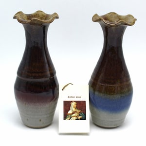 May include: Two brown and blue ceramic vases with a ruffled top. The vases are glazed in shades of brown, blue, and white. The vases are labeled "Esther Vase".