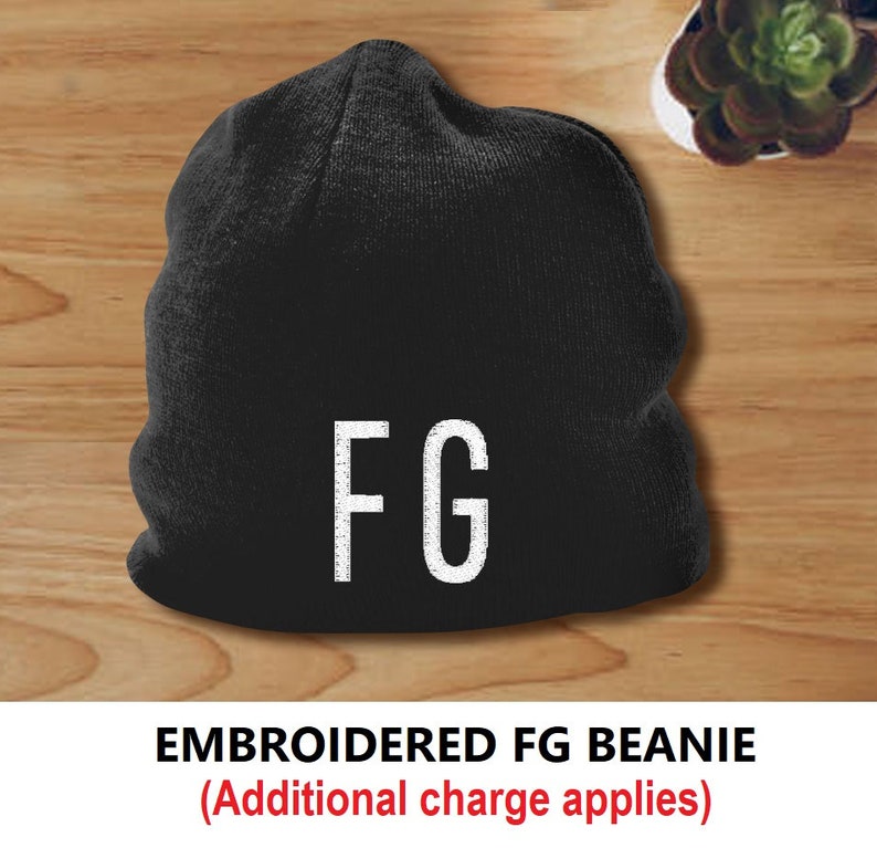 Puede incluir: Gorro negro con las letras blancas "FG" bordadas en la parte delantera. El gorro se muestra sobre una superficie de madera. El texto "EMBROIDERED FG BEANIE" est&aacute; debajo.