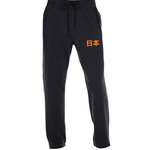 May include: Black sweatpants with an orange Japanese word "日本" (Japan) printed on the left leg. The sweatpants have a drawstring waistband and a pocket on the left side.