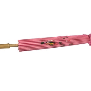 May include: A pink and white paper umbrella with a wooden handle. The umbrella is closed and has a floral design.