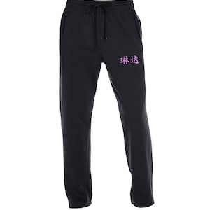 May include: Black sweatpants with a drawstring waist and a pocket on the left side. The sweatpants have the Chinese characters "林达" embroidered on the right leg in pink.