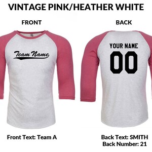 May include: A baseball style t-shirt in pink and heather grey. The front of the shirt features the text "Team Name" in a vintage style font. The back of the shirt has the text "YOUR NAME" and the number "00" in a black block font.