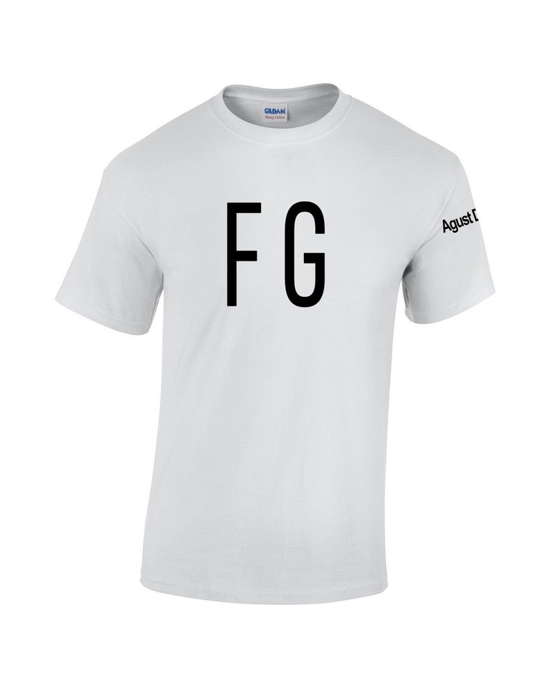 Puede incluir: Camiseta blanca de manga corta con las letras "FG" en fuente negra grande en la parte delantera. La manga tiene el texto "Agust D" impreso en negro. La camiseta est&aacute; hecha de un material suave y c&oacute;modo.