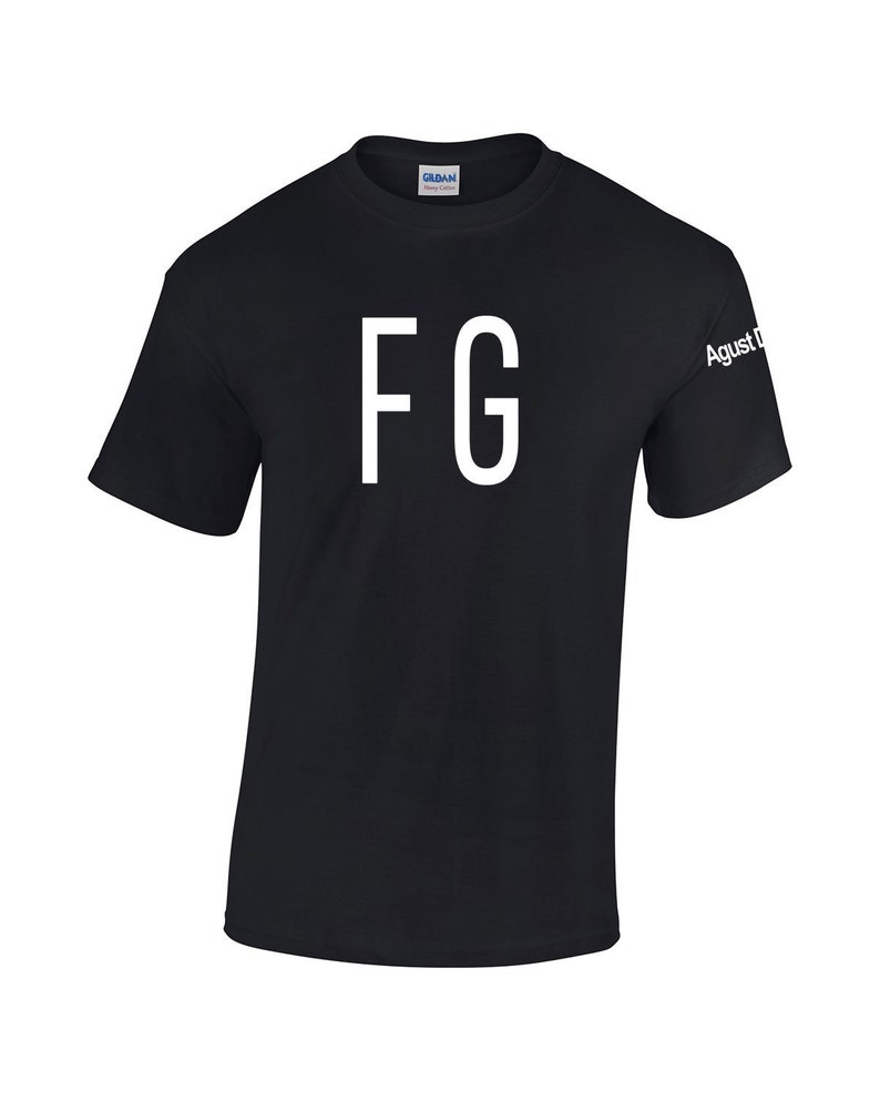 Puede incluir: Camiseta negra con las letras blancas "FG" estampadas en la parte delantera. La manga tiene el texto "Agust D" en blanco. La camiseta est&aacute; hecha de un material suave y tiene cuello redondo.