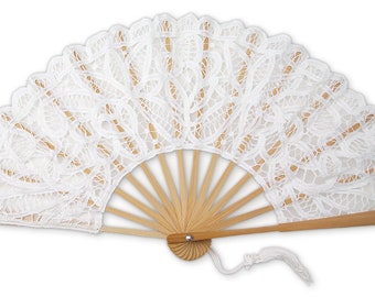 May include: A white lace hand fan with a wooden handle and ribs. The fan is open, displaying a delicate floral lace pattern. A white tassel hangs from the base. The fan is a decorative accessory.