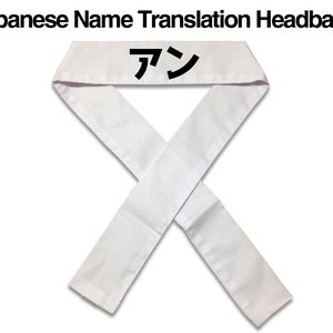 Puede incluir: Diadema blanca con la palabra japonesa "アン" impresa en negro.