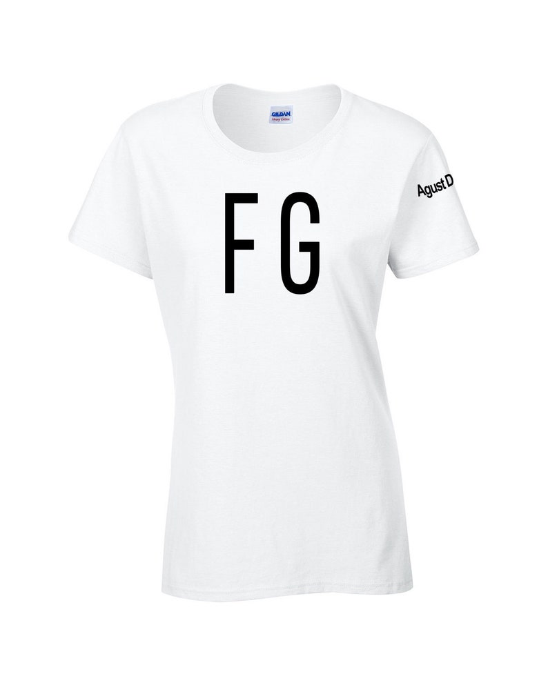Puede incluir: Camiseta blanca de cuello redondo con las letras "FG" en fuente negra grande en la parte delantera. La manga tiene el texto "Agust D" impreso en negro. La camiseta est&aacute; hecha de un material suave.