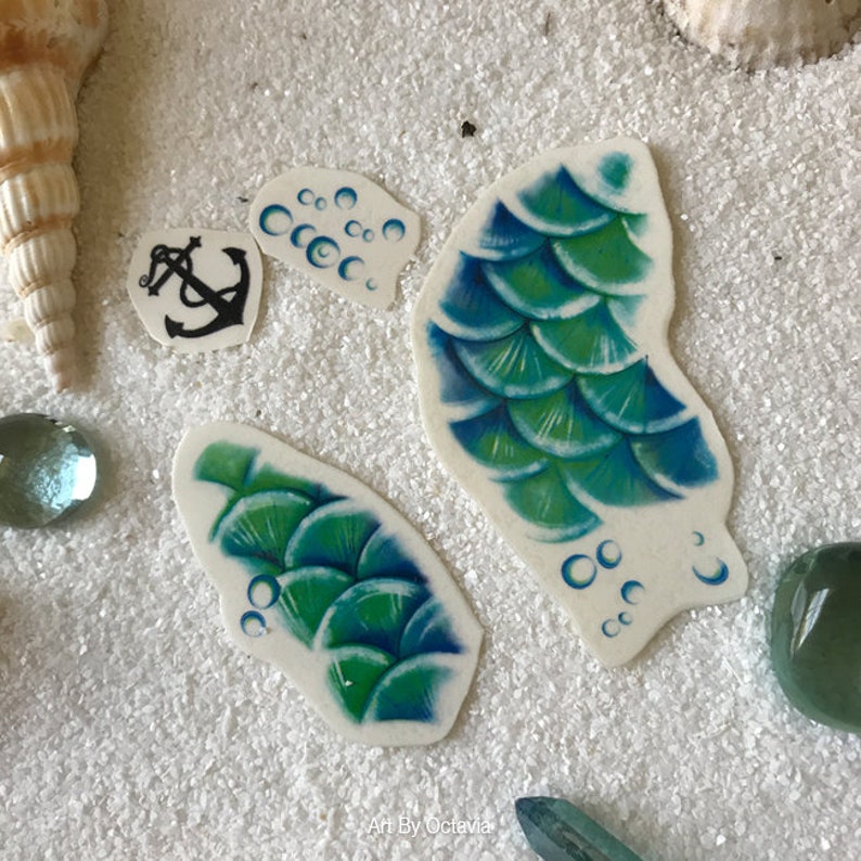 May include: Four temporary tattoos featuring a mermaid tail, bubbles, and an anchor. The tattoos are on a white background.