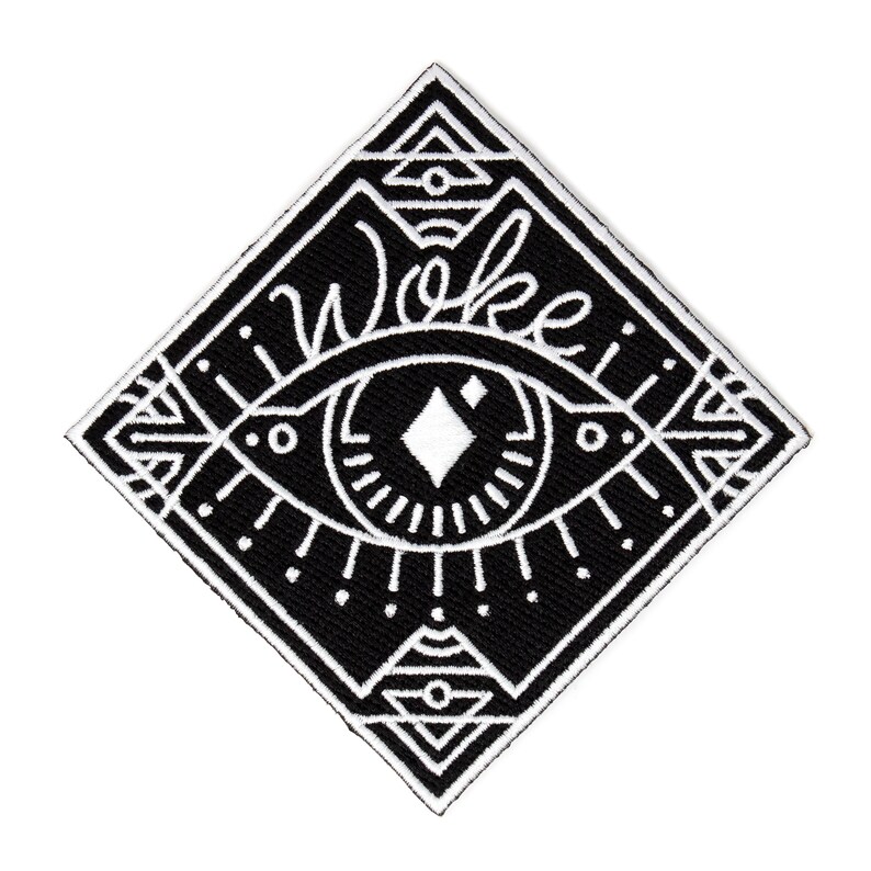 May include: Black and white embroidered patch with a stylized eye and geometric shapes. The word "Woke" is written above the eye.