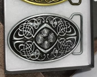 May include: Two oval-shaped belt buckles with intricate Celtic knot designs. The top buckle is gold with a dark brown background, while the bottom buckle is silver with a black background.