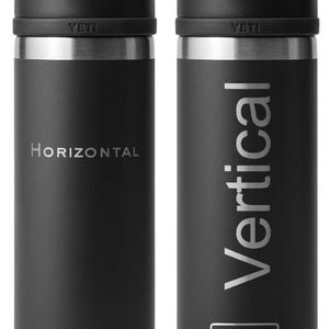 May include: Two black YETI Rambler 12 oz. stainless steel tumblers with a black lid and a carrying handle. The left tumbler has the word "HORIZONTAL" engraved on the side. The right tumbler has the word "VERTICAL" engraved on the side. The tumblers are shown side-by-side with the words "Engraving Direction" at the top of the image.