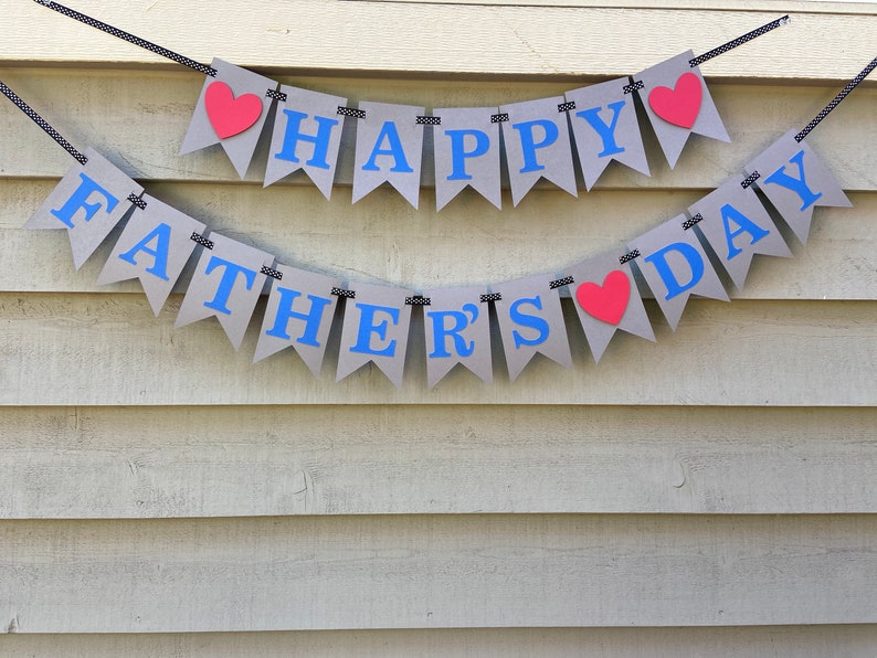 May include: A gray banner with blue letters that reads "Happy Father's Day" with red hearts between the words.