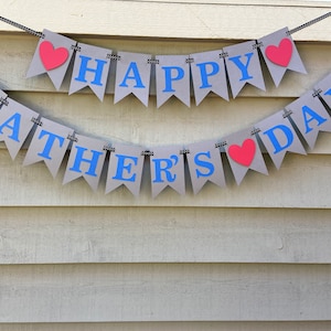 May include: A gray banner with blue letters that reads "Happy Father's Day" with red hearts between the words.