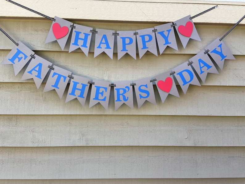 May include: A gray banner with blue letters that reads "Happy Father's Day" with red hearts between the words.
