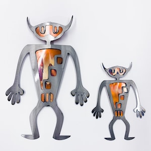 May include: Two metal sculptures of stylized figures with orange and brown accents. The larger figure is about 12 inches tall and the smaller figure is about 6 inches tall.