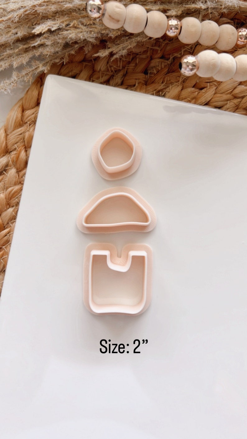 Puede incluir: Tres cortadores de galletas de pl&aacute;stico rosa en forma de c&iacute;rculo, semic&iacute;rculo y rect&aacute;ngulo con un recorte. Los cortadores est&aacute;n dispuestos verticalmente sobre una superficie blanca. Tama&ntilde;o: 5 cm