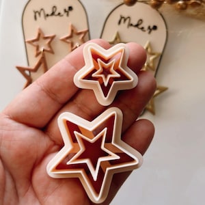 Puede incluir: Dos juegos de cortadores de galletas con forma de estrella. El juego más grande tiene tres estrellas, una dentro de la otra. El juego más pequeño tiene dos estrellas, una dentro de la otra. Ambos juegos están hechos de plástico beige claro.