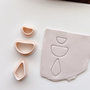 Könnte beinhalten: Ein Set rosa Plastik-Ausstecher in Form von abstrakten geometrischen Formen. Die Ausstecher befinden sich auf einer weißen Oberfläche.