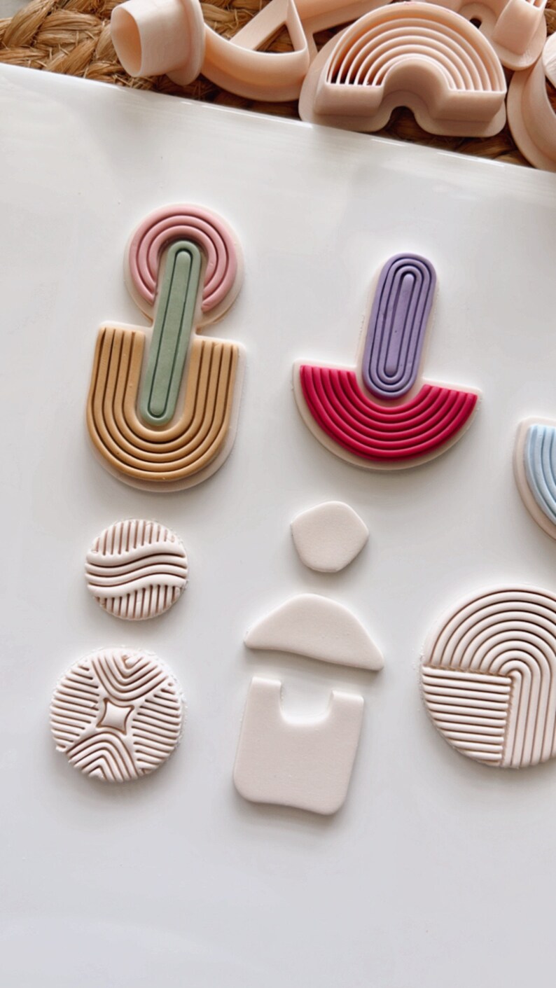 Puede incluir: Un conjunto de moldes de arcilla polim&eacute;rica para crear formas geom&eacute;tricas. Los moldes son de varios colores, incluyendo rosa, morado, verde y rojo. Los moldes est&aacute;n dispuestos sobre una superficie blanca.