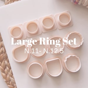 May include: A set of 10 pink plastic ring mandrels for jewelry making. The mandrels are in different sizes, ranging from 11 to 12.5. The set is labeled "Large Ring Set N.11 - N.12.5".