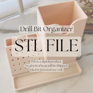May include: A light pink plastic drill bit organiser with a compartment for storing drill bits and a tray for holding small parts. The organiser is labelled "Drill Bit Organiser" and "STL FILE". The text "This is a digital product. No physical item will be shipped. File for personal use only" is also included.