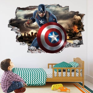 Peut inclure: Un autocollant mural repr&eacute;sentant Captain America per&ccedil;ant un mur, tenant son bouclier. L'image montre un paysage urbain et une sc&egrave;ne de bataille en arri&egrave;re-plan. Un enfant regarde l'autocollant, avec un lit en bois et des jouets au premier plan.