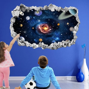 Könnte beinhalten: Ein 3D-Wandaufkleber, der eine rissige Wand zeigt, die eine farbenfrohe Galaxie mit Planeten und einem wirbelnden Nebel enthüllt. Zwei Kinder betrachten den Aufkleber, eines davon zeigt darauf.