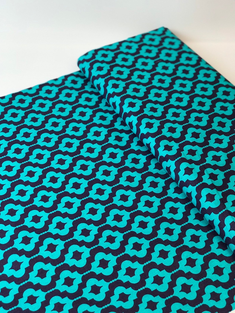 May include: Teal and navy blue fabric with a repeating geometric pattern. The fabric is folded in half, showing the pattern on both sides.